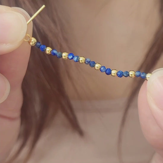 Close-up of a gold and blue beaded earring worn on an ear. Perfect birthday gift for mom