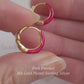 Close-up view of pink and gold enamel hoop earrings featuring twisted gold detail and vibrant green enamel finish.