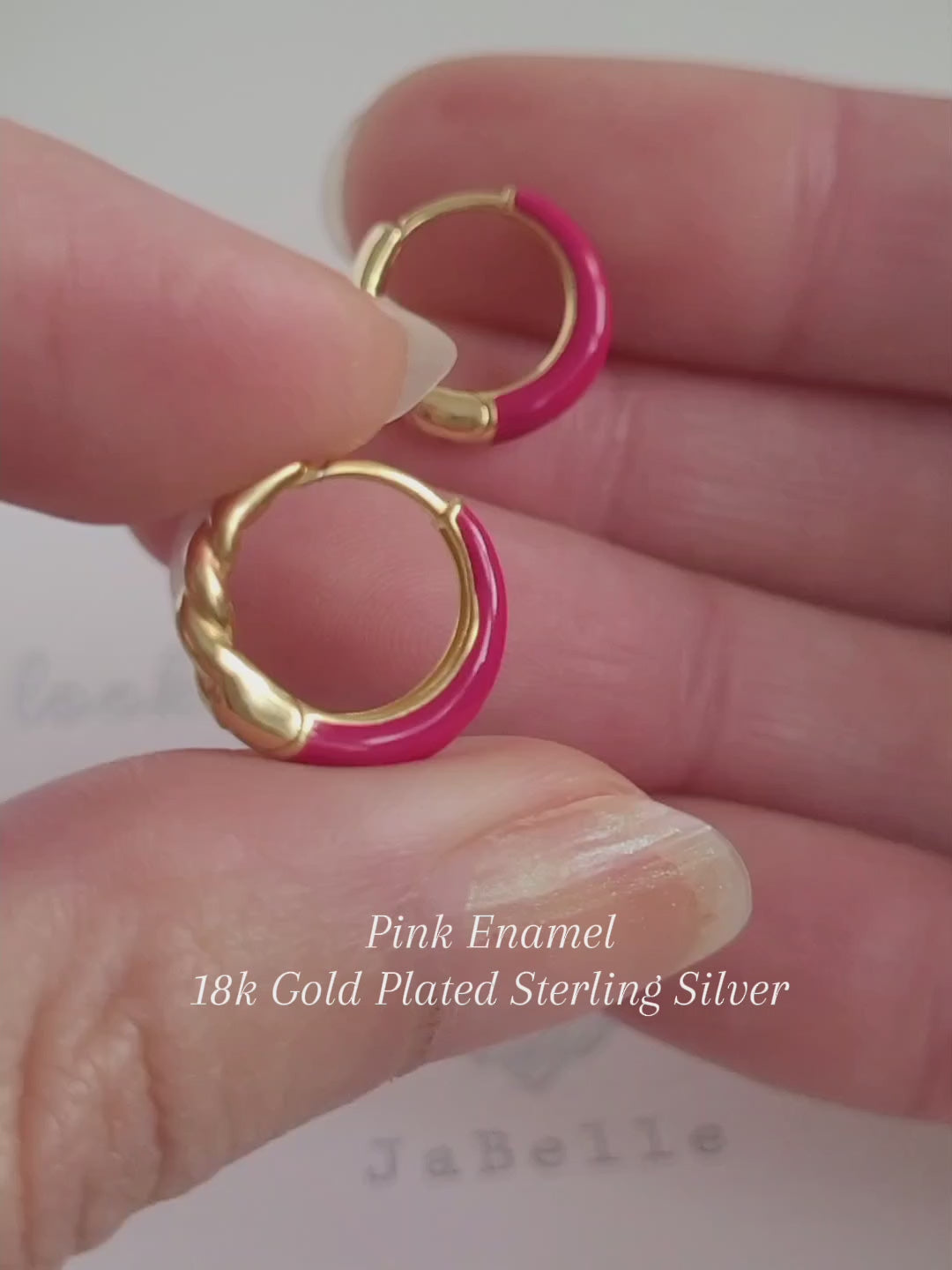 Close-up view of pink and gold enamel hoop earrings featuring twisted gold detail and vibrant green enamel finish.