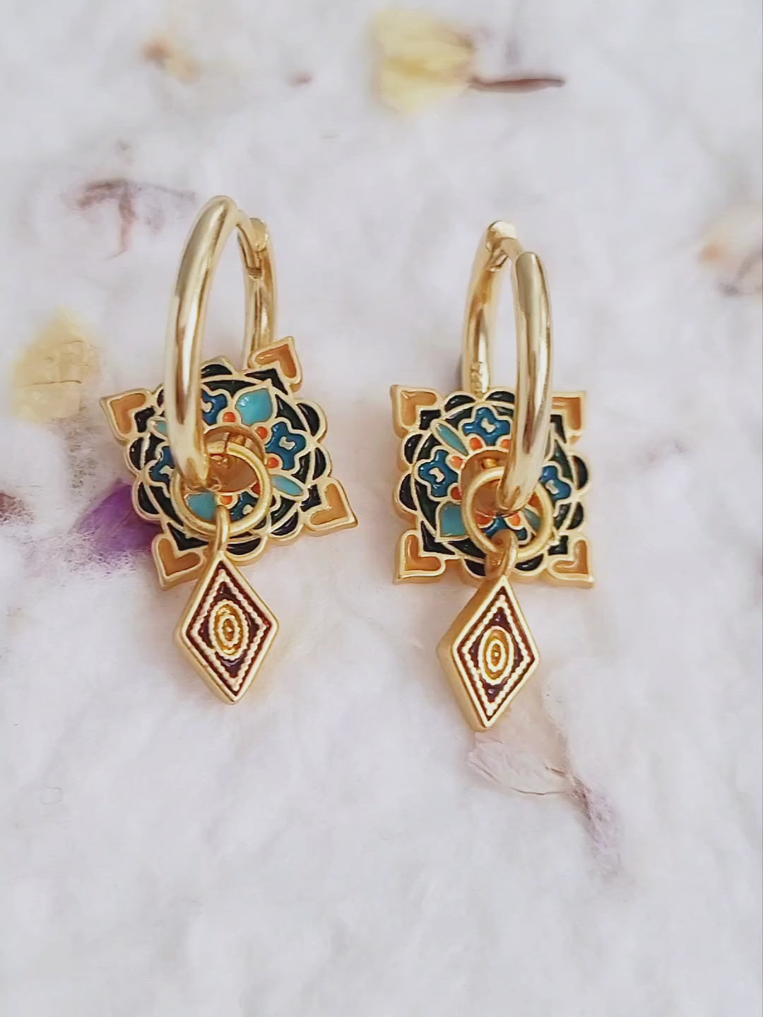 Artistic gold hoop earrings adorned with vibrant enamel tile motifs and small diamond-shaped pendants, perfect for a unique statement look.