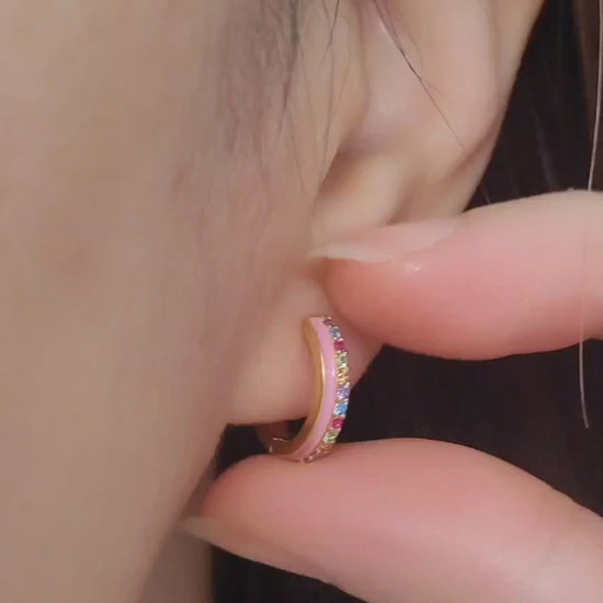 Close up of a woman wearing statement pink enamel hoop earrings with rainbow crystal styled for a boho chic look. Crafted in gold plated sterling silver.