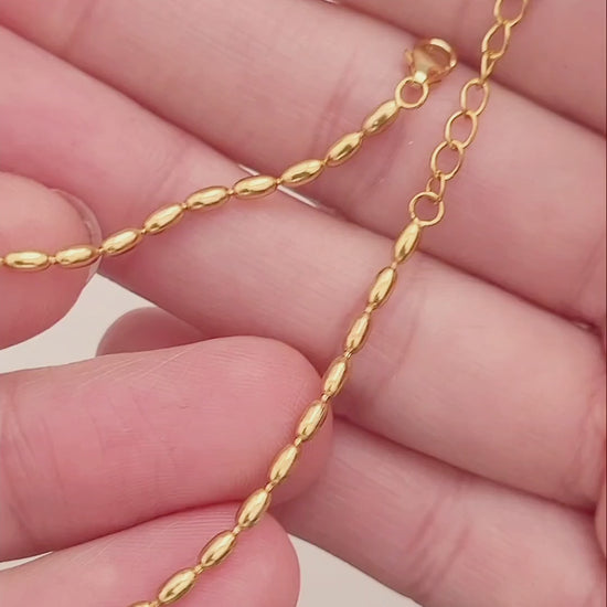 Close-up of a woman's hand wearing the elegant and dainty gold-plated oval beaded bracelet, highlighting its lustrous finish and intricate bead arrangement.