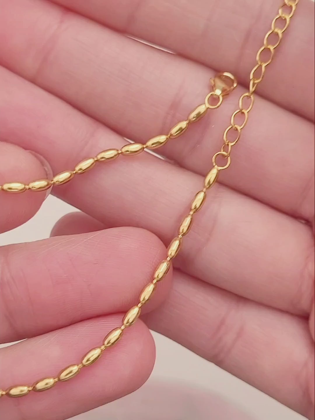 Close-up of a woman's hand wearing the elegant and dainty gold-plated oval beaded bracelet, highlighting its lustrous finish and intricate bead arrangement.