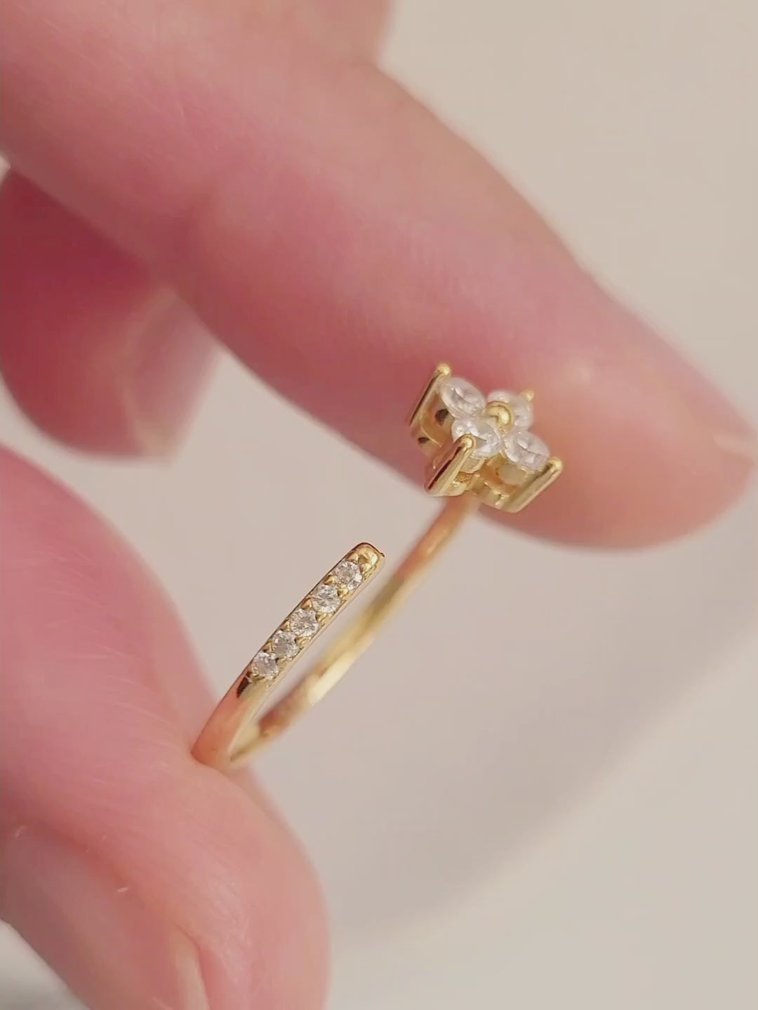 Close-up of a woman's hand showcasing a gold Clover ring featuring four brilliant diamonds.