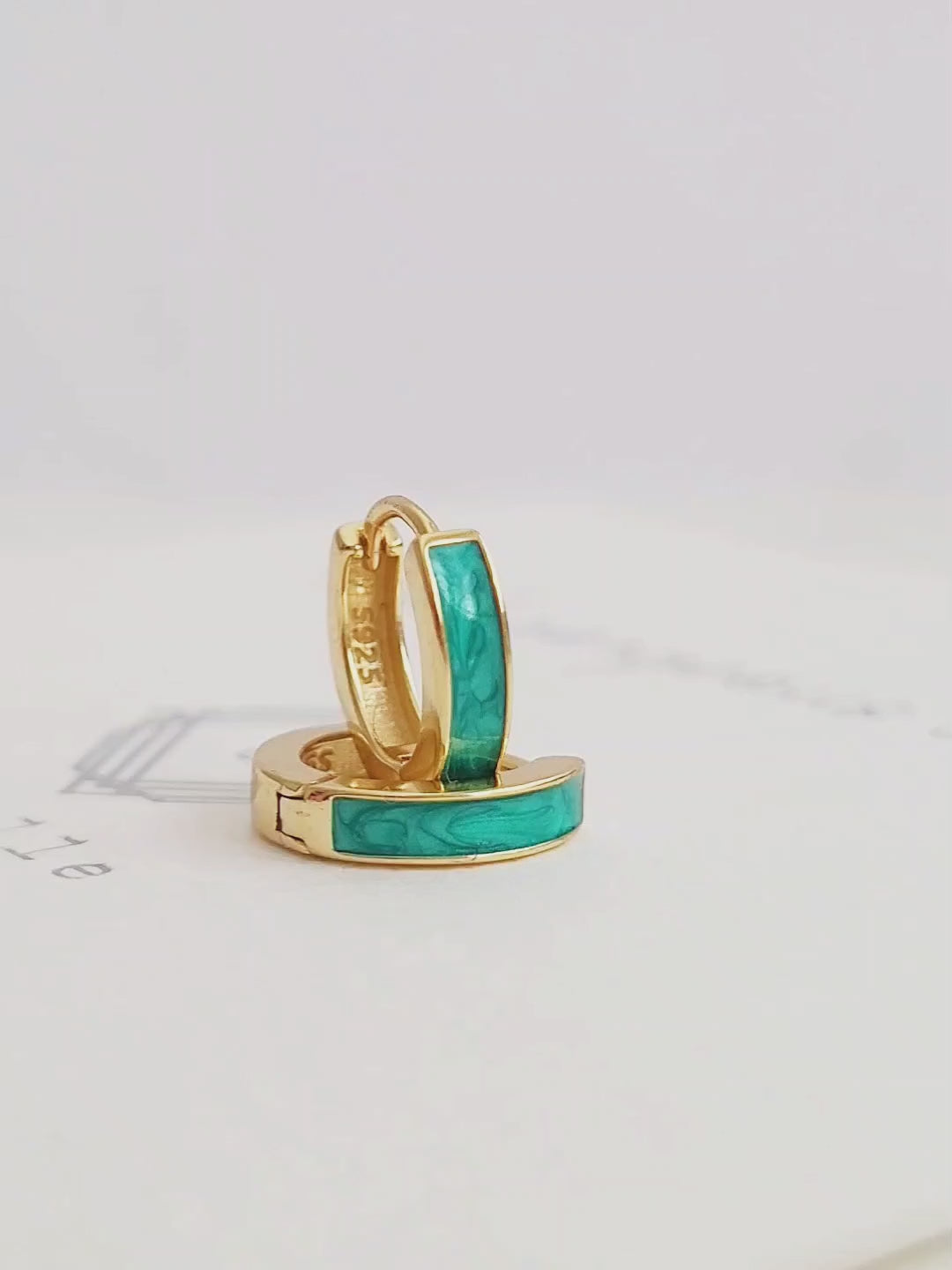 Elegant gold and turquoise green enamel huggie hoop earrings, featuring a chic design that adds flair to your everyday style.