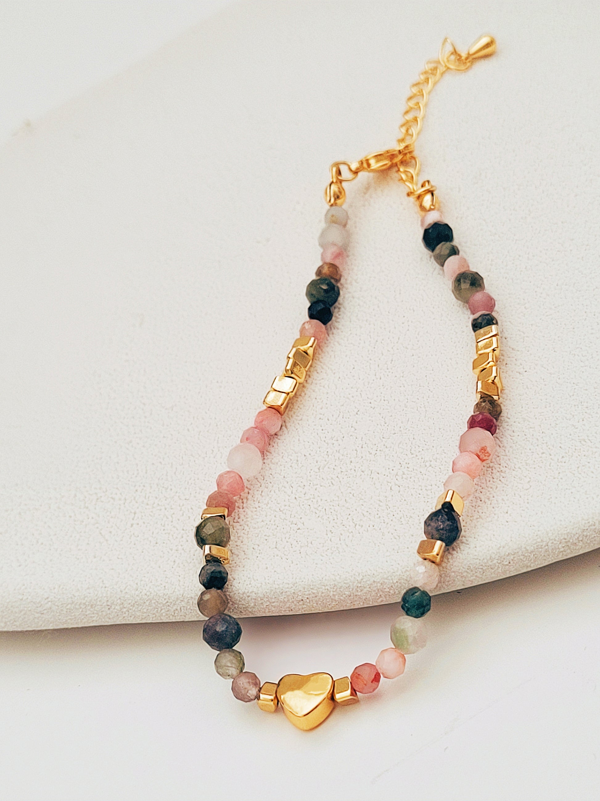 A delicate rainbow gemstone bracelet featuring faceted aventurine, jasper, and rose quartz beads, accented with gold vermeil heart charm at the center. The bracelet has a gold clasp and adjustable chain.