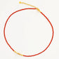 Necklace with red beaded onyx gemstone and gold beads on a white background