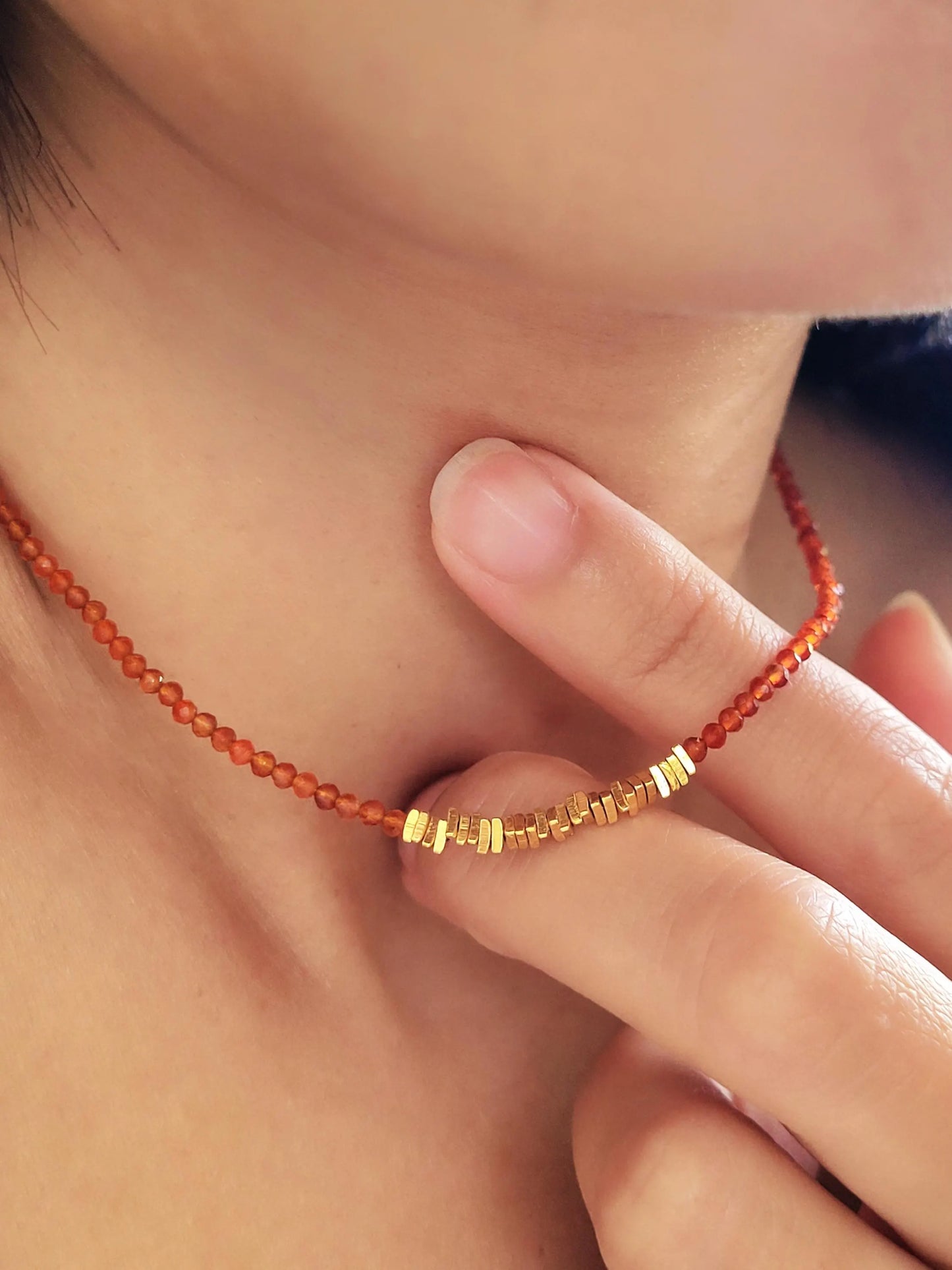 Close-up of a woman wearing a red onyx beaded gemstone necklace with gold vermeil beads, perfect summer beach jewellery