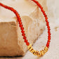 Close up of a red onyx gold vermeil choker necklace on an aesthetic beige color stone.