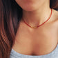 Close-up of a person wearing a red beaded necklace with a gold clasp.