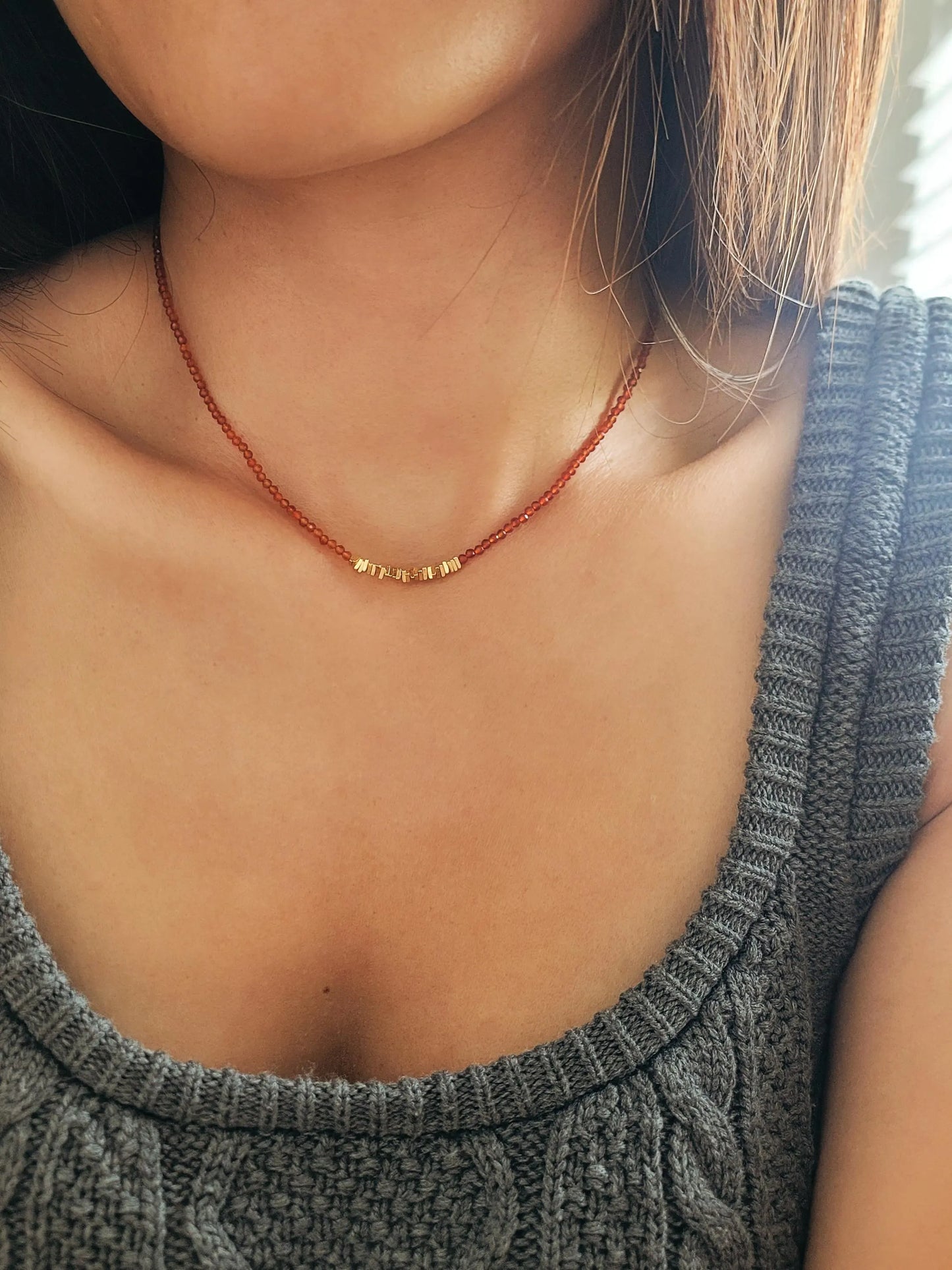 Woman wearing a red onyx choker necklace with 22k gold vermeil beads with knitted casual wear, perfect for summer necklace layering.