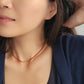 Close-up of a woman wearing a red onyx beaded choker necklace with a neutral background