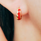 Eye-catching red wavy enamel huggie hoops, designed to bring a playful flair to your jewelry collection.