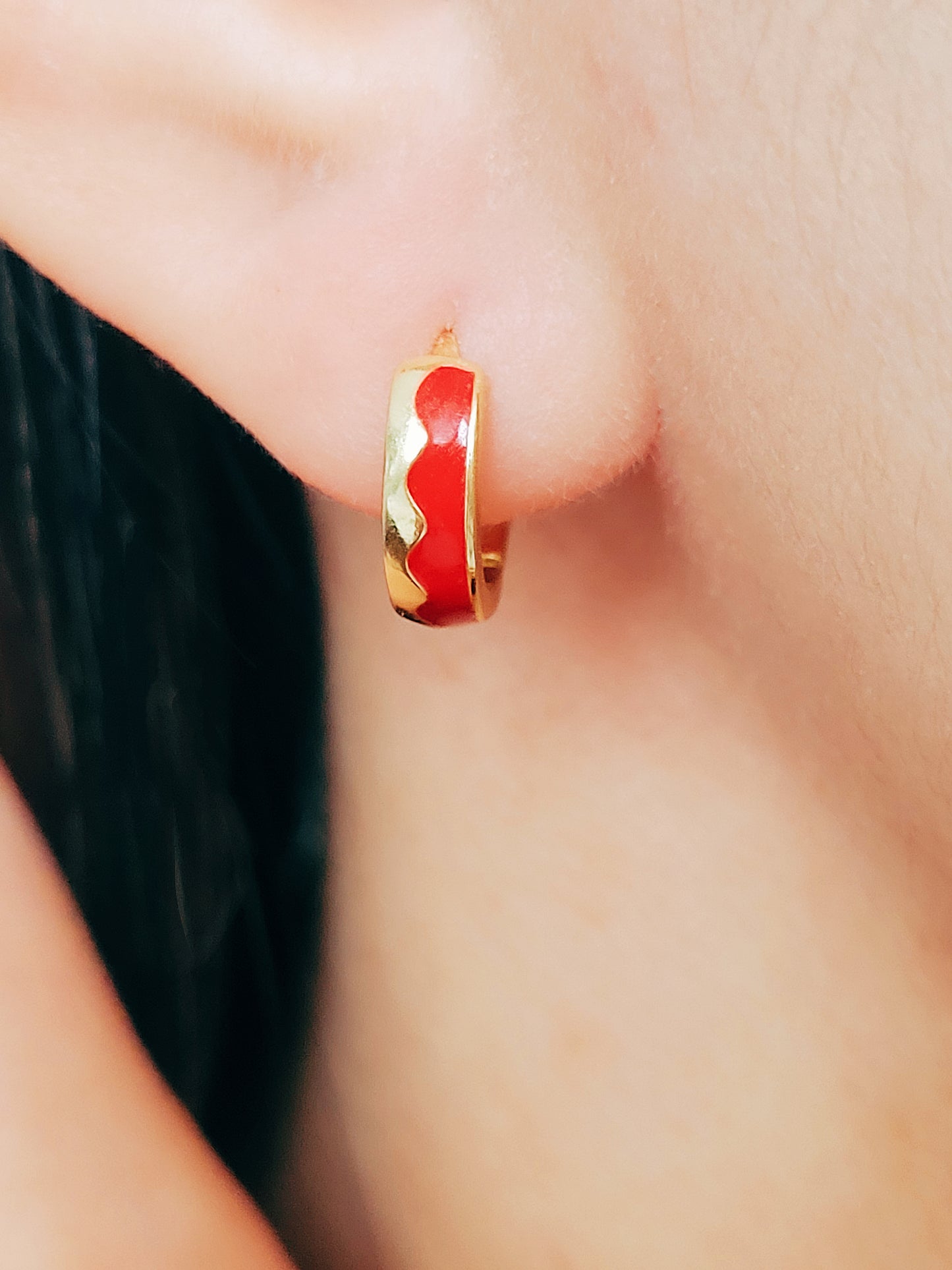 Eye-catching red wavy enamel huggie hoops, designed to bring a playful flair to your jewelry collection.