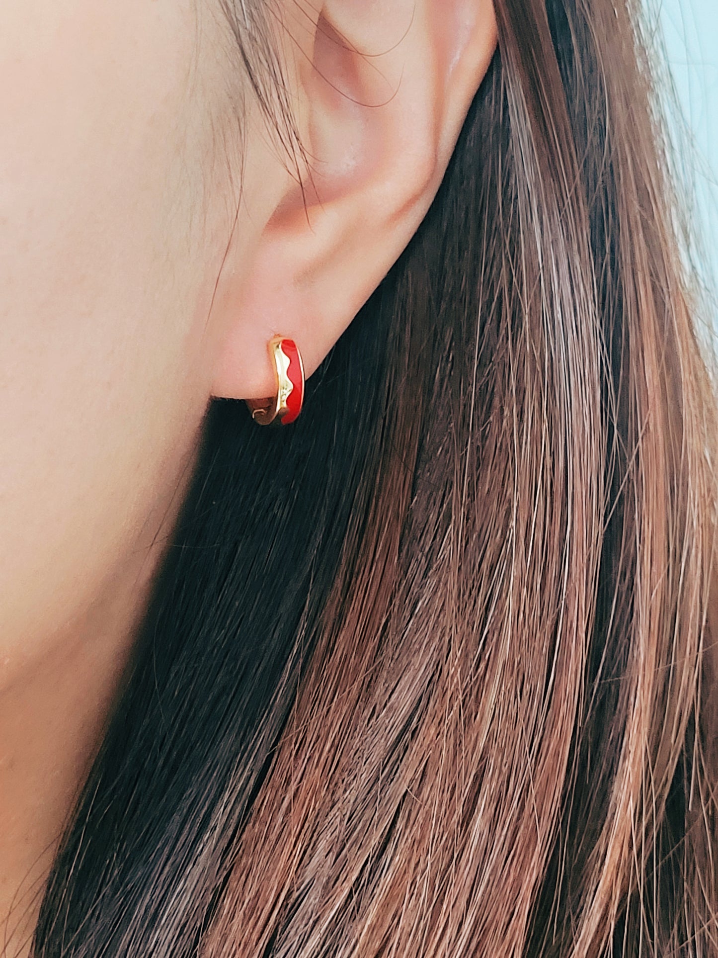 Bright red wavy enamel huggie hoops, a chic accessory that enhances your look with a touch of fun and elegance.