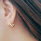 A woman showcases a stylish gold ear cuff paired with hammered hoop earrings, highlighting her unique fashion sense