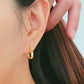 A woman showcases her elegance with hammered gold hoop earrings, exuding timeless sophistication.