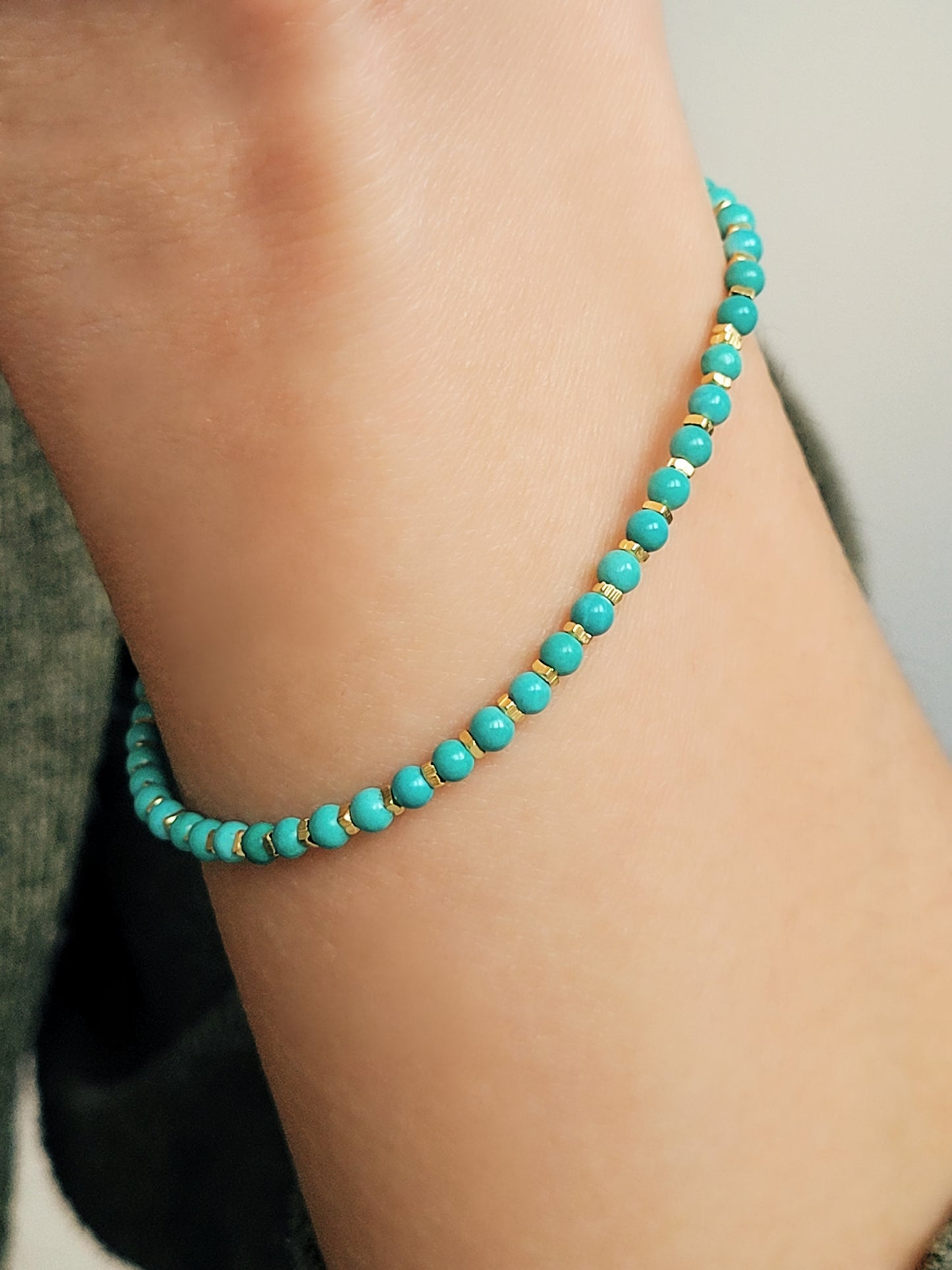 Close up of a woman's wrist wearing a Gold Turquoise beaded bracelet. Crafted in high quality natural turquoise gemstone intersecting with gold vermeil beads.