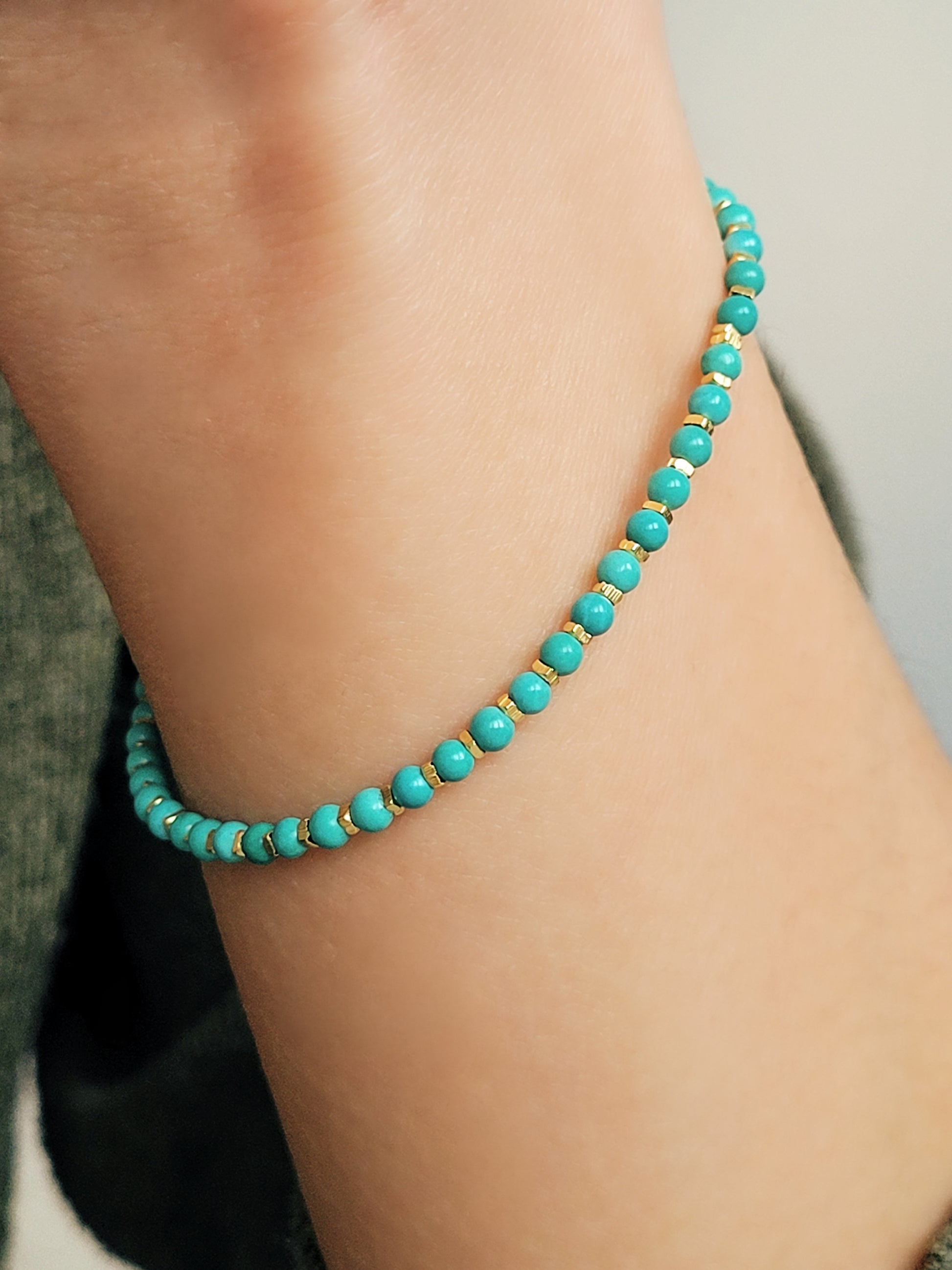 Close up of a woman's wrist wearing a Gold Turquoise beaded bracelet. Crafted in high quality natural turquoise gemstone intersecting with gold vermeil beads.