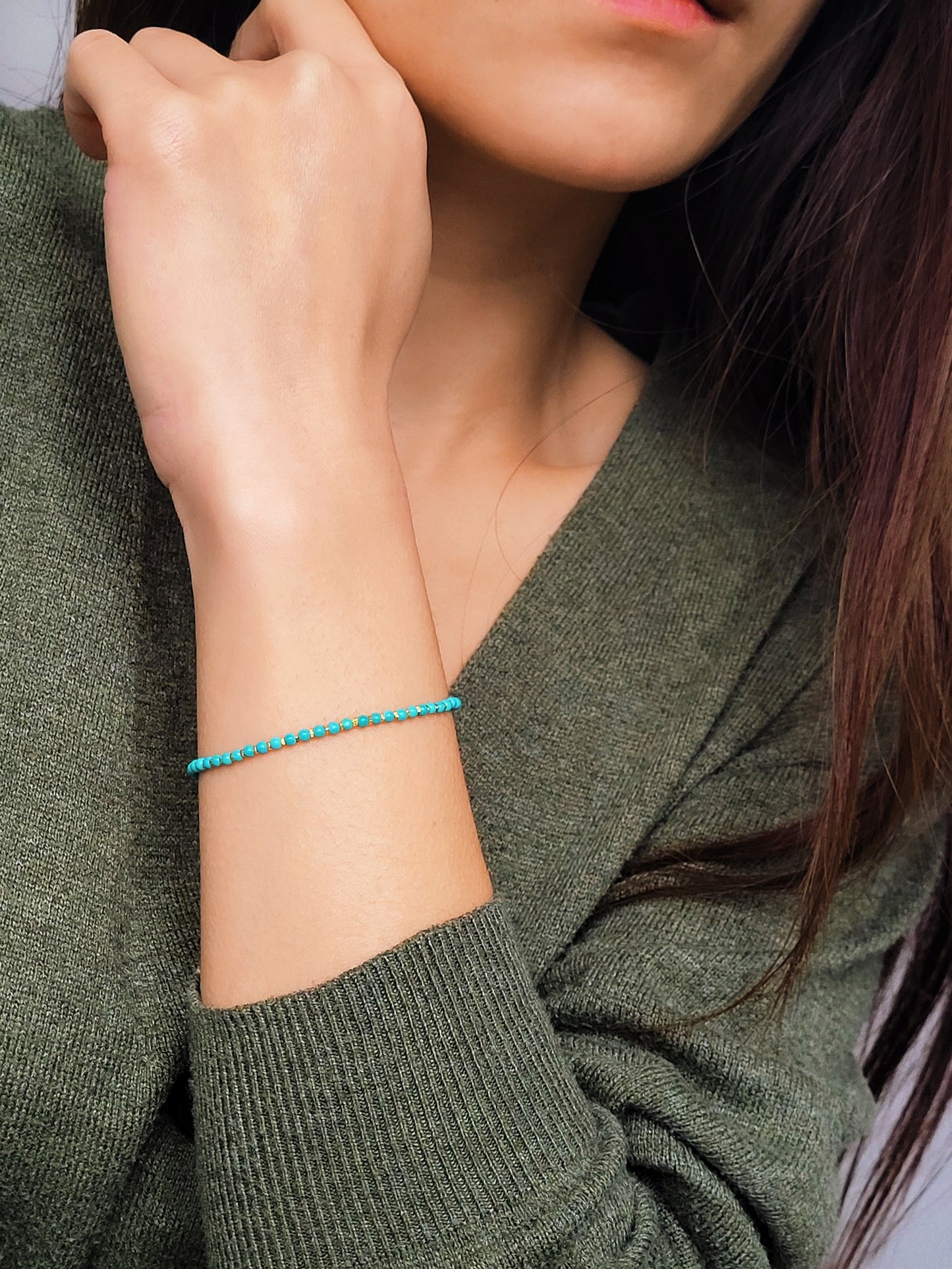 Close up of a woman's wrist wearing a Gold Turquoise beaded bracelet. Crafted in high quality natural turquoise gemstone intersecting with gold vermeil beads.