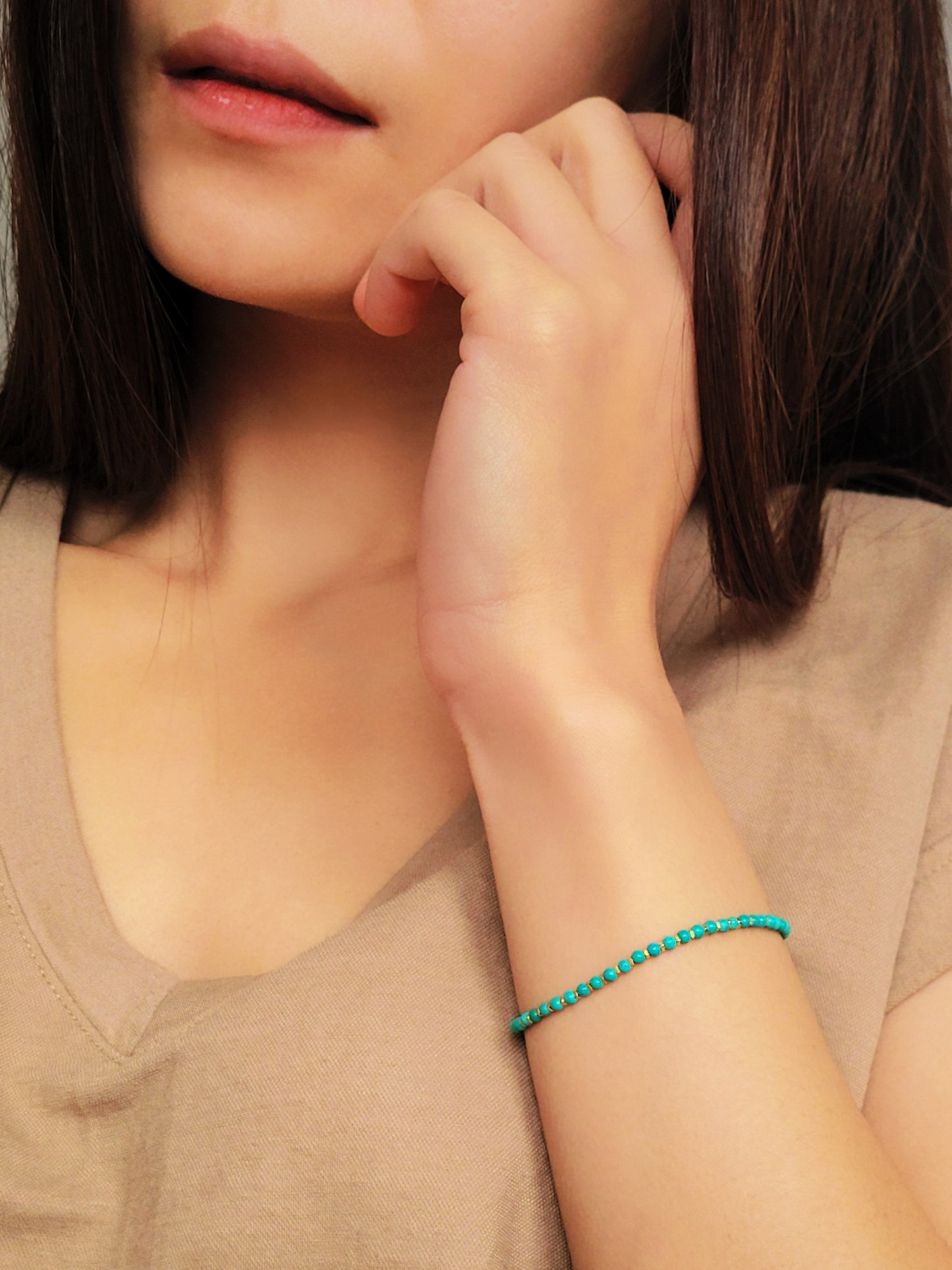 Close up of a woman's wrist wearing a Gold Turquoise beaded bracelet. Crafted in high quality natural turquoise gemstone intersecting with gold vermeil beads.