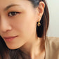 Model wearing gold vermeil dangle earrings with tiger's eye gemstone, minimalist and elegant style.