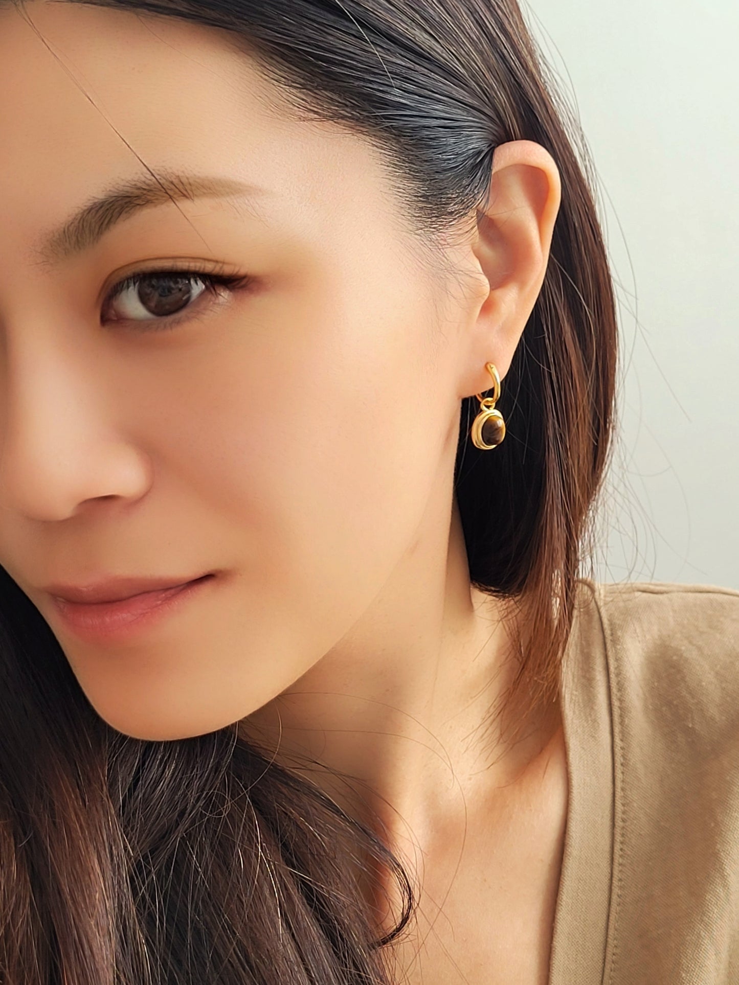 Model wearing gold vermeil dangle earrings with tiger's eye gemstone, minimalist and elegant style.