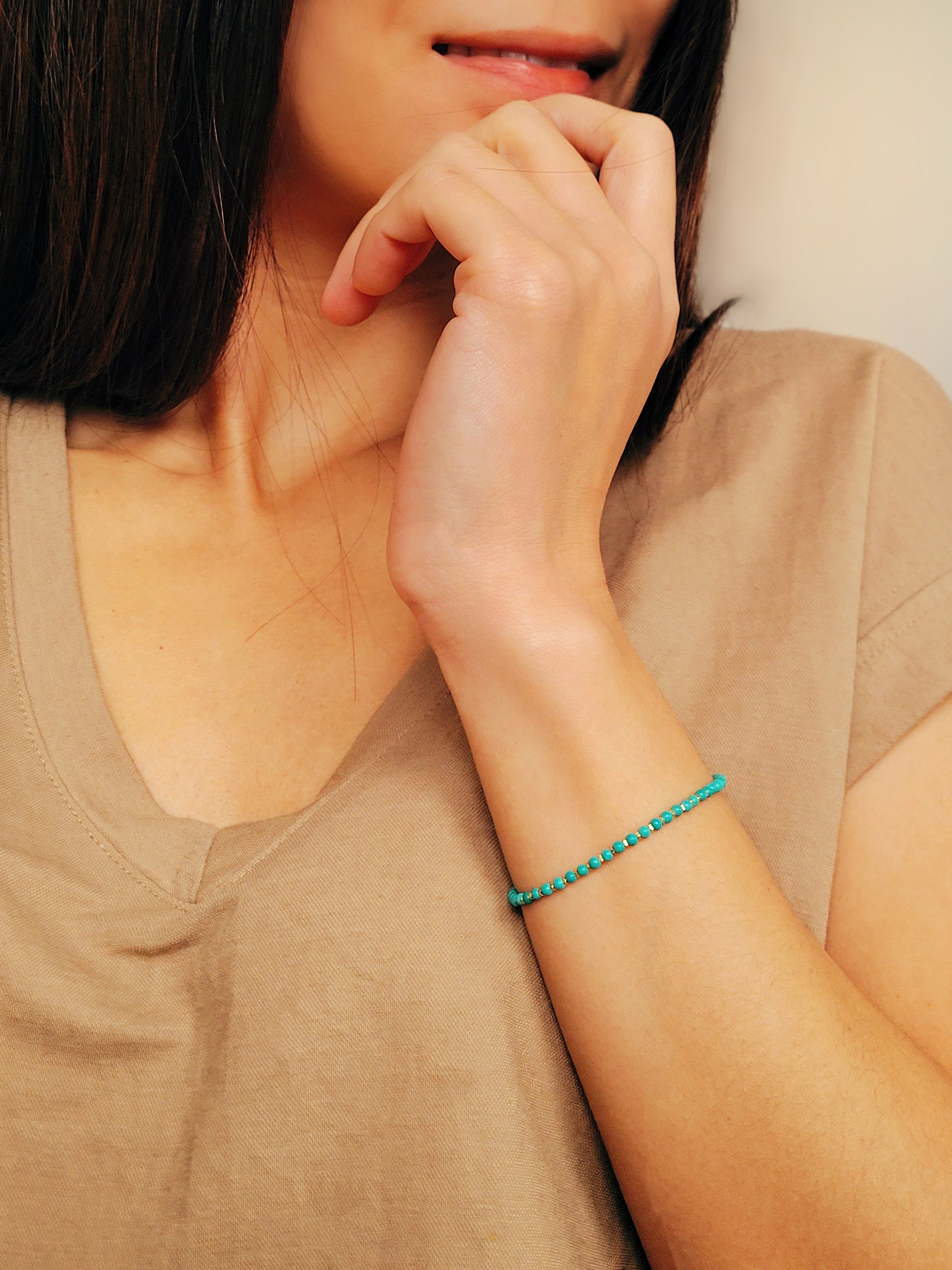 Close up of a woman's wrist wearing a Gold Turquoise beaded bracelet. Crafted in high quality natural turquoise gemstone intersecting with gold vermeil beads.