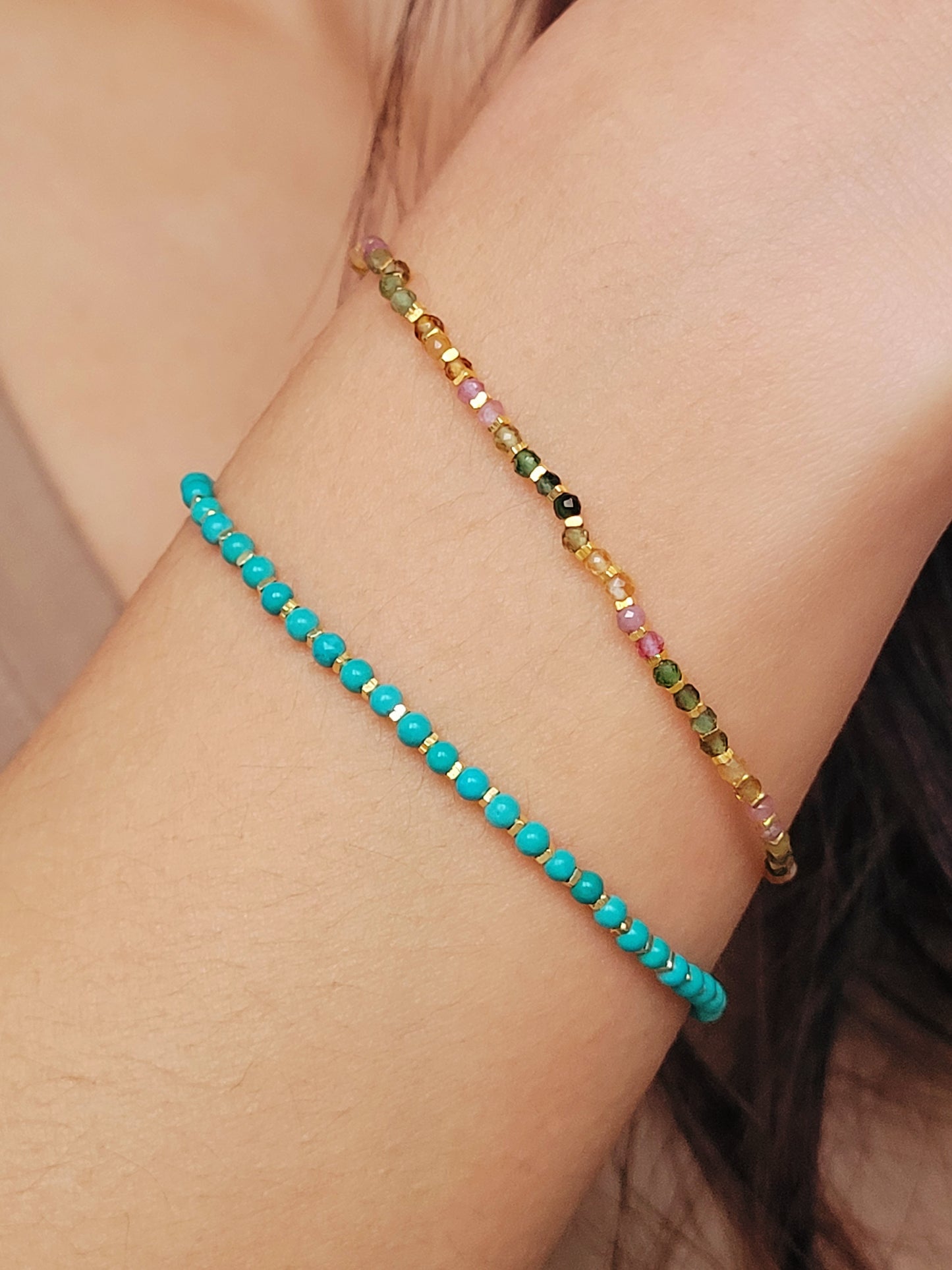 Close up of a woman's wrist wearing a Gold Turquoise beaded bracelet. Crafted in high quality natural turquoise gemstone intersecting with gold vermeil beads.