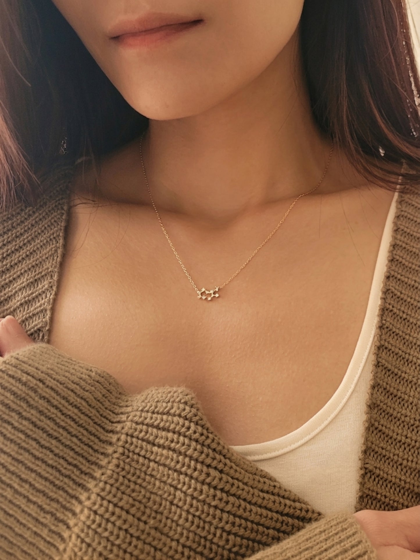 Close-up of a woman wearing a dainty gold sagittarius necklace showcasing the luxury aesthetic and pendant scale.