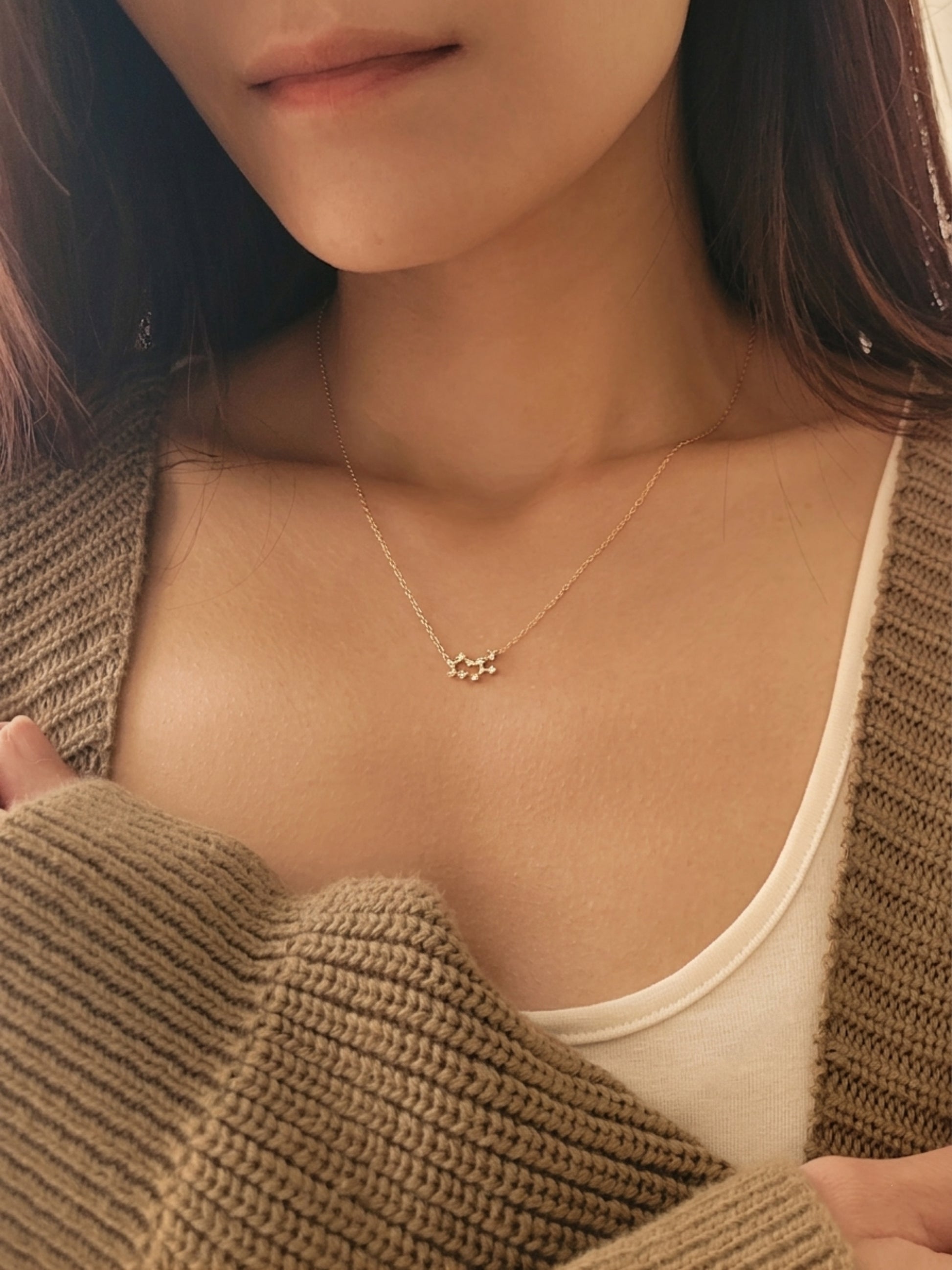 Close-up of a woman wearing a dainty gold sagittarius necklace showcasing the luxury aesthetic and pendant scale.