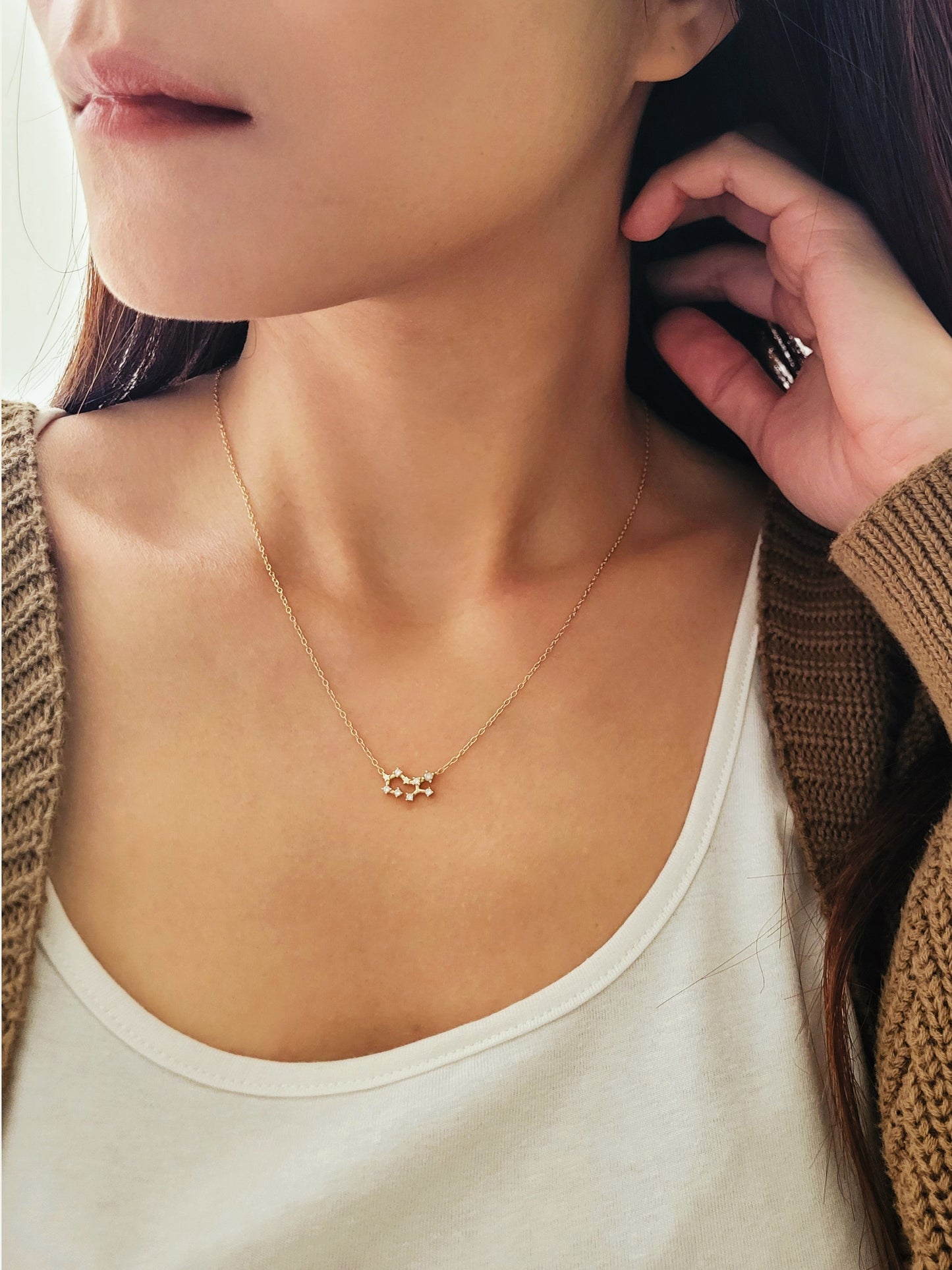 Close-up of a woman wearing a dainty gold sagittarius necklace showcasing the luxury aesthetic and pendant scale.