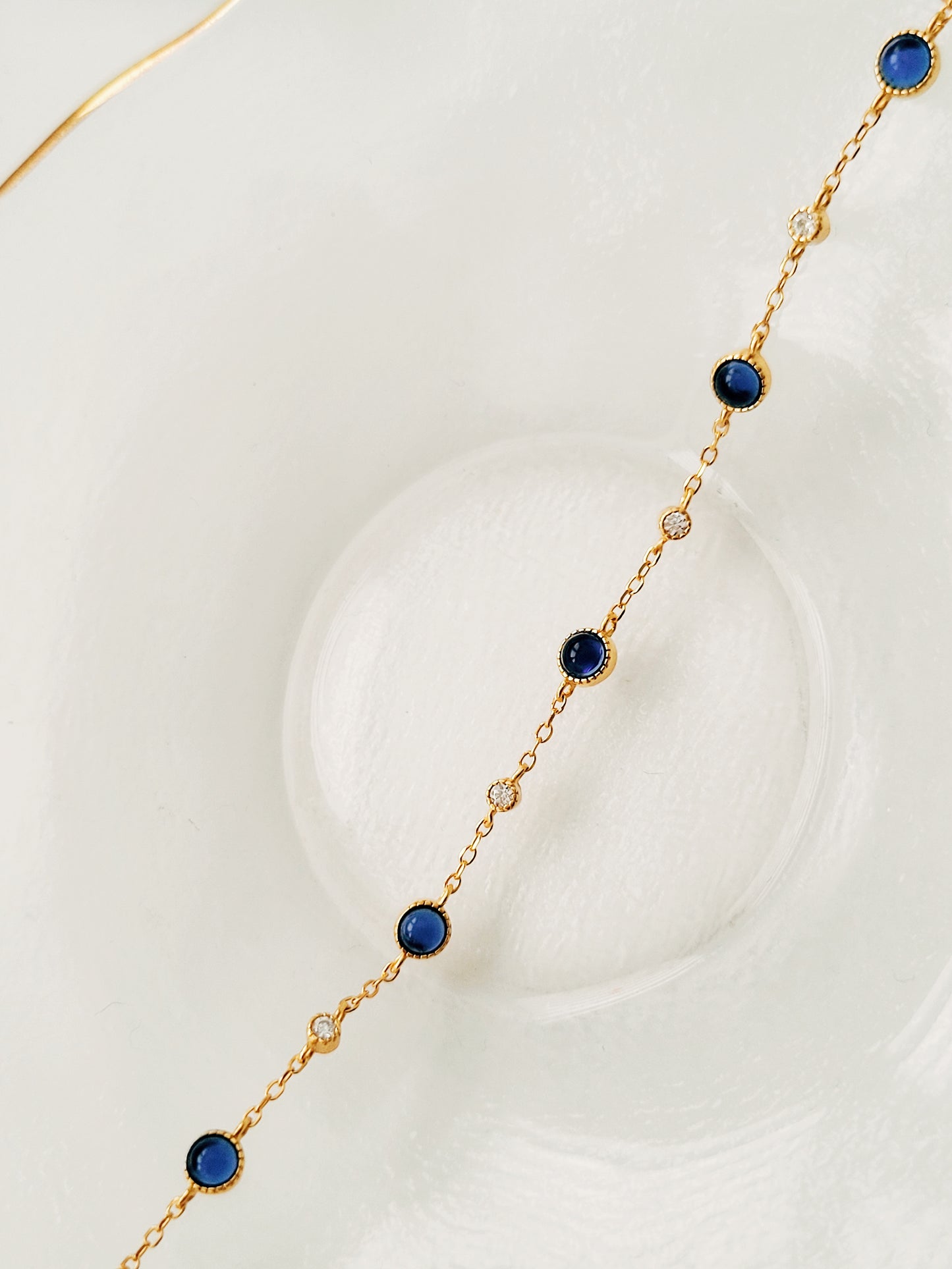 A luxurious 18ct gold plated over sterling silver chain adorned with exquisite blue sapphires and sparkling zircons, showcasing a stunning sapphire station bracelet design.