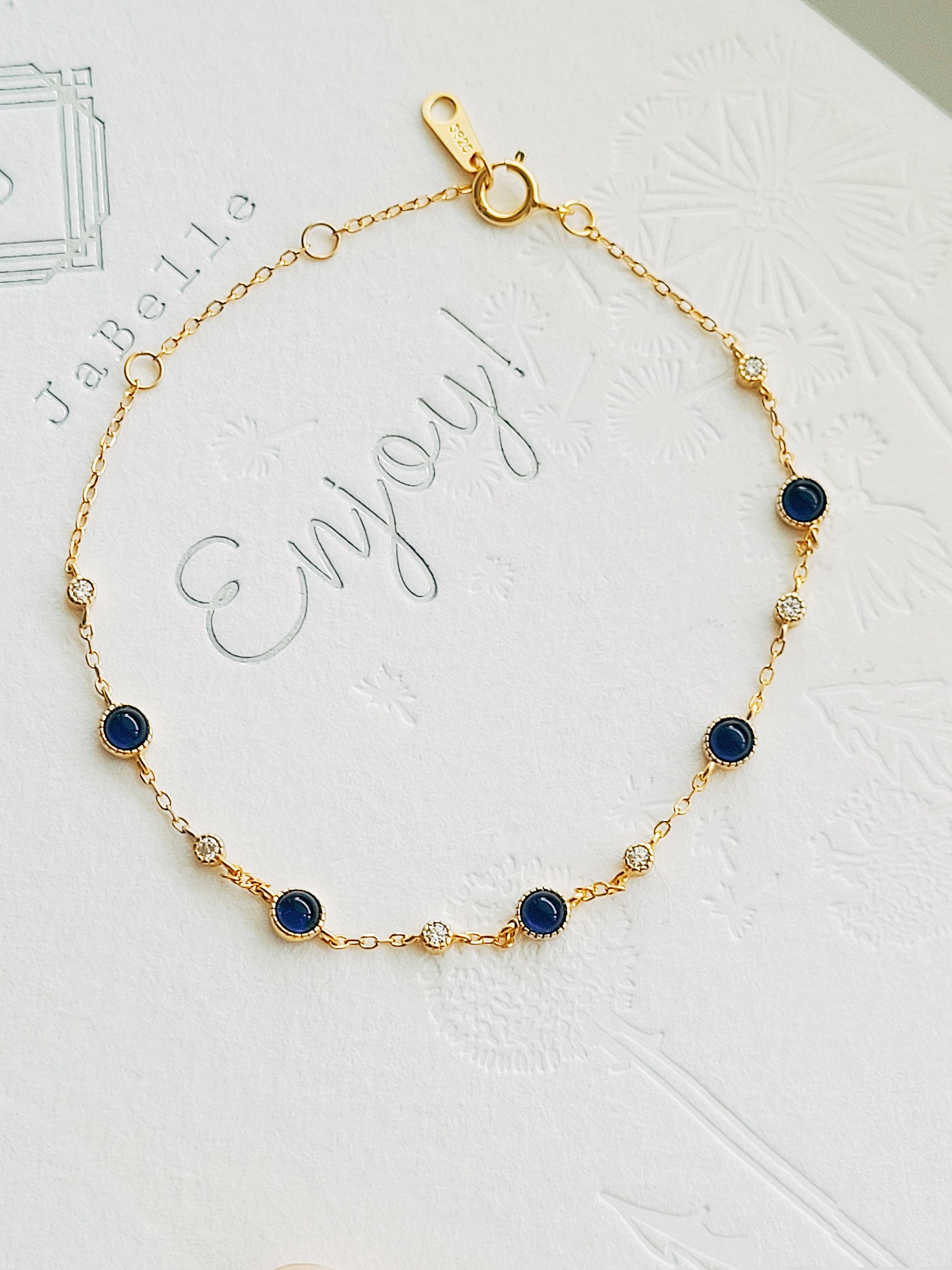 A luxurious 18ct gold plated over sterling silver chain adorned with exquisite blue sapphires and sparkling zircons, showcasing a stunning sapphire station bracelet design.