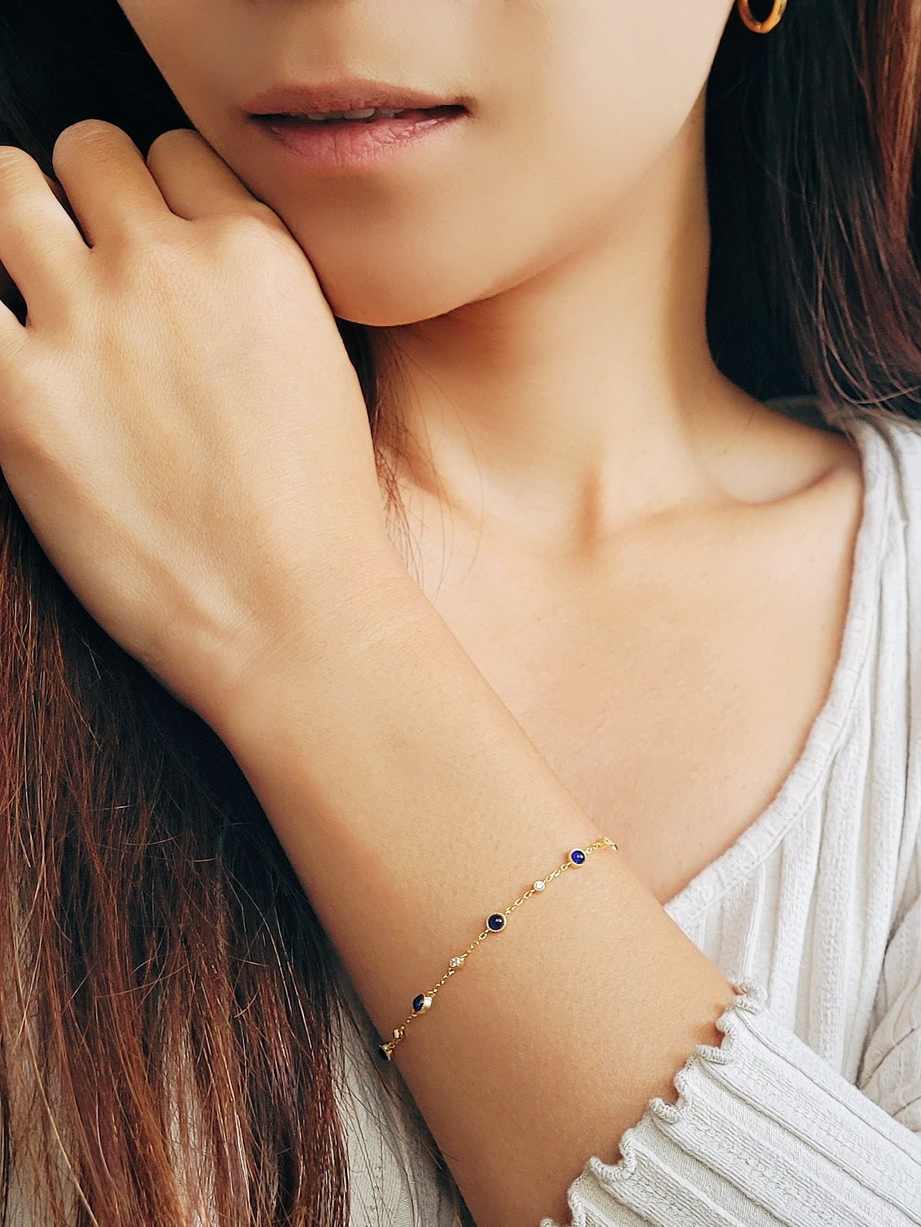 A woman wears a stunning gold bracelet embellished with vibrant blue sapphire stones, epitomizing refined luxury and style.