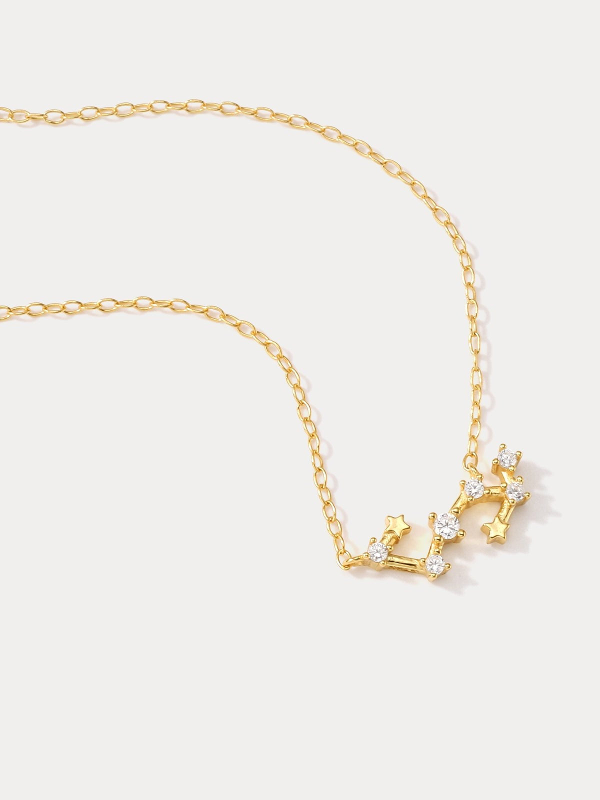 A dainty gold necklace with a pendant featuring a stylized Scorpio zodiac constellation sign with sparkling zircons.