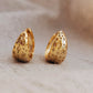 Pair of gold star hoop earrings with intricate starry designs on a beige background