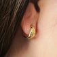 Gold star huggie hoop earring worn on an ear with a close-up view