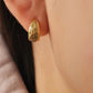 Gold earring featuring celestial star pattern worn on an ear with a neutral background