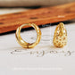Gold huggie hoop star earrings with measurements on a neutral background