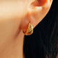 Close up of a starry huggie hoop earring worn on a woman's ear