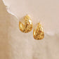 Gold hoop star earrings on a textured beige background