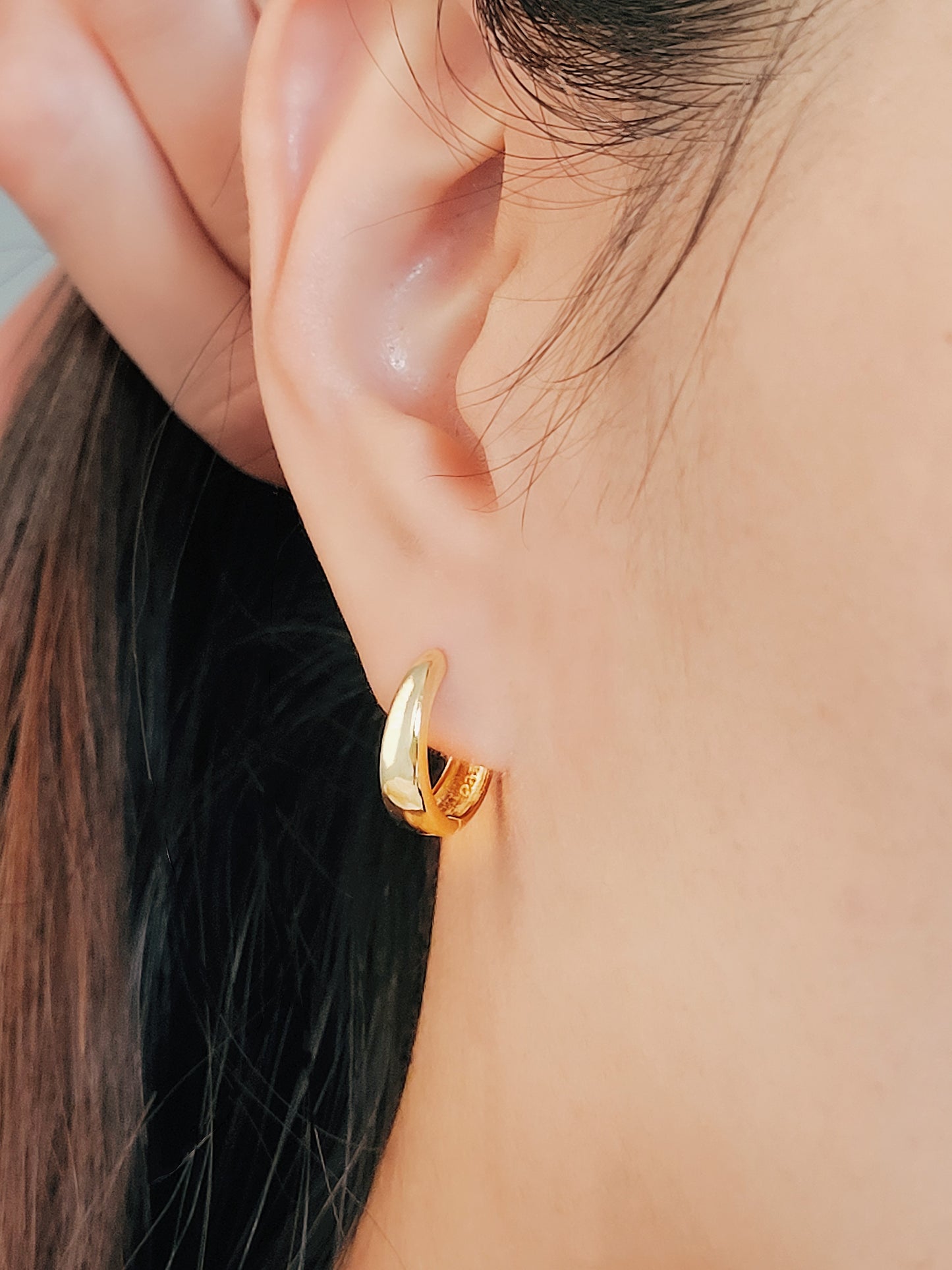 Elegant tapered hoop earrings with a sleek design that gracefully hug the earlobe, offering a contemporary look for any occasion.