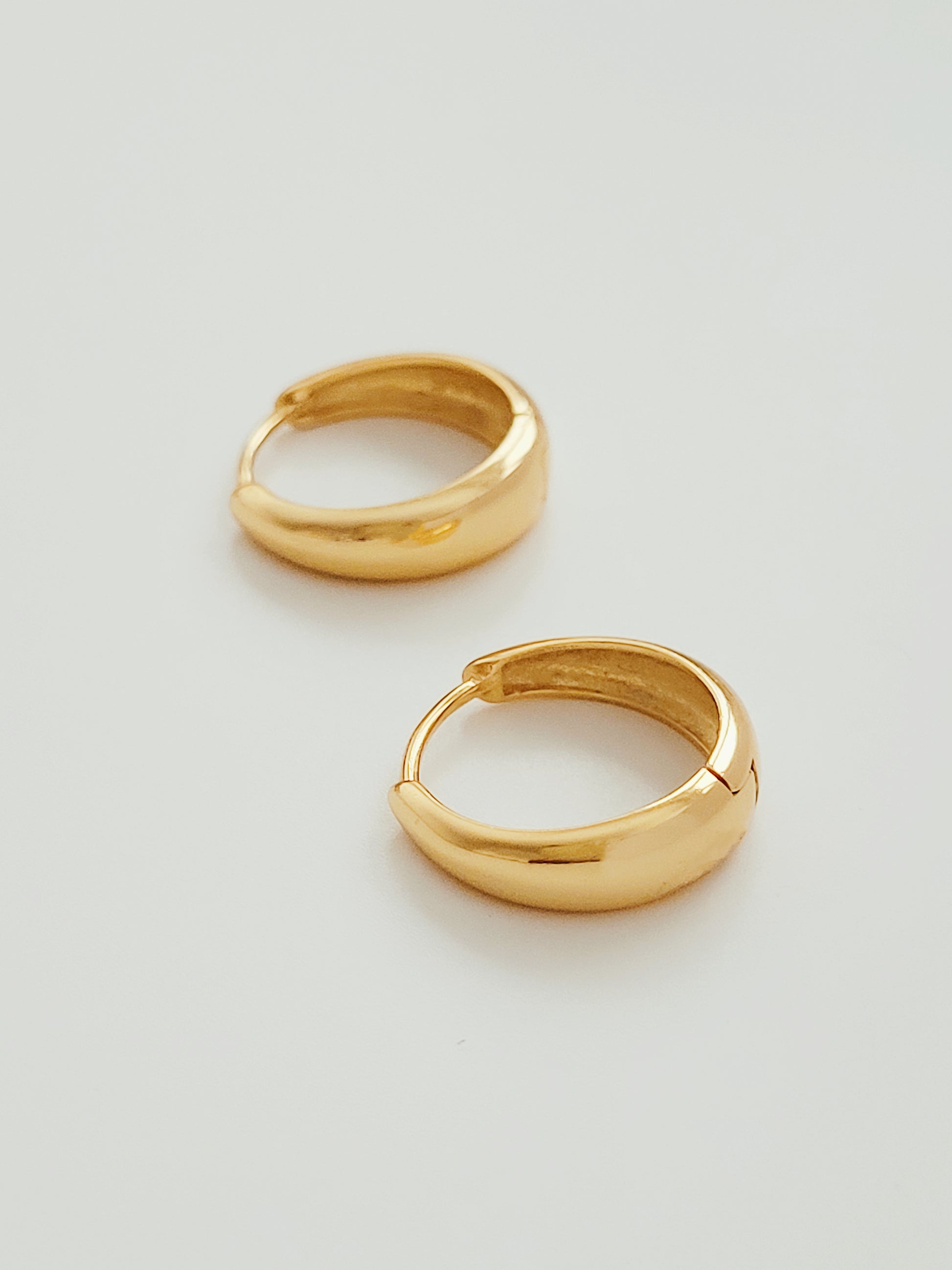 Stylish tapered gold hoop earrings with a delicate small gold hoop, perfect for adding a touch of elegance.