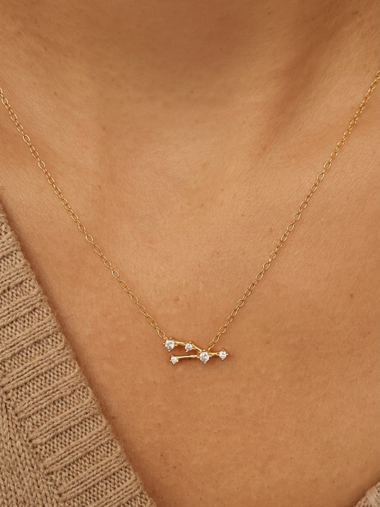 Close-up of a woman wearing a dainty gold Taurus necklace, showcasing the luxury aesthetic and pendant scale. Crafted in 14k gold vermeil.