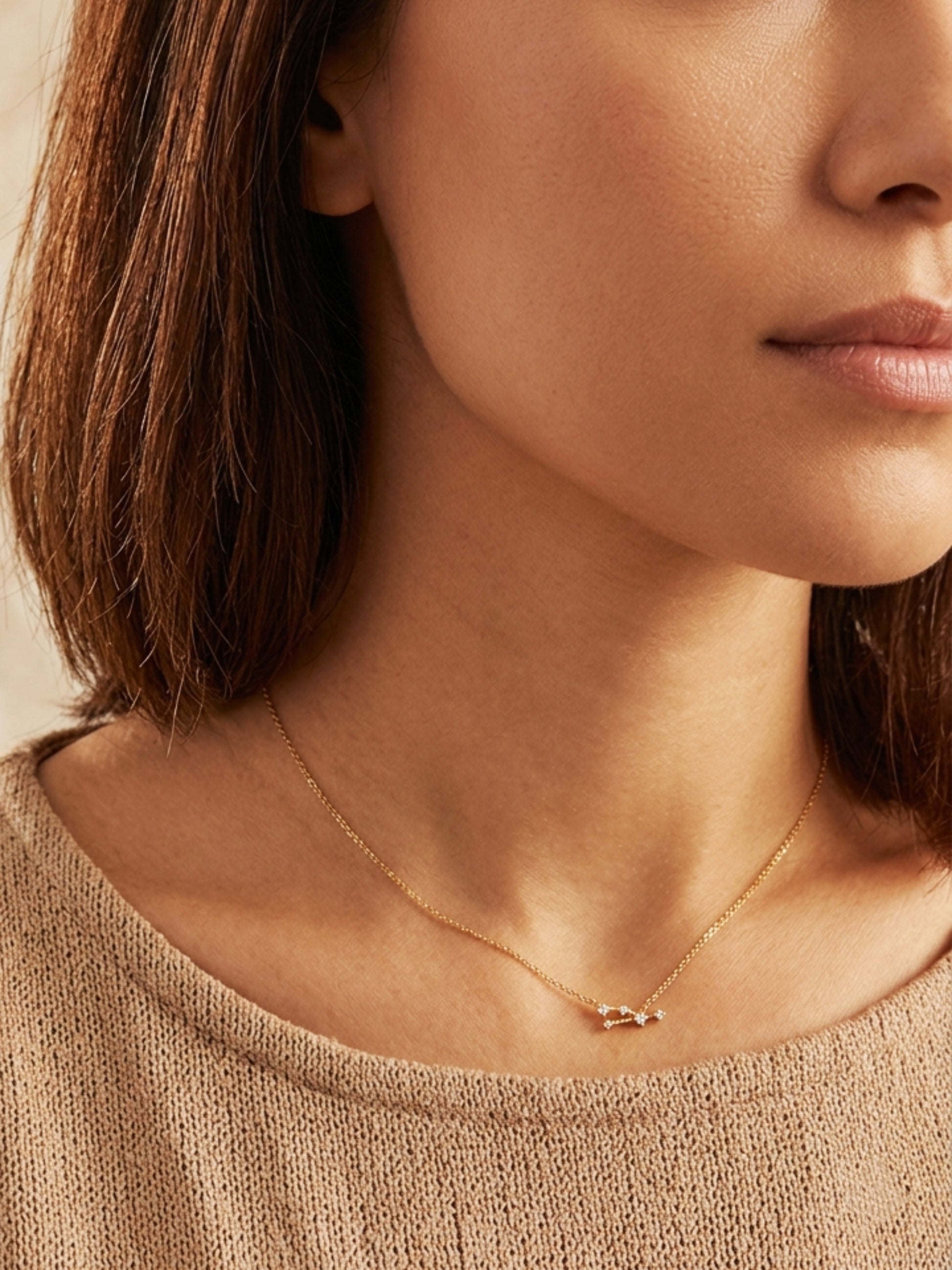 Close-up of a woman wearing a dainty gold Taurus necklace, showcasing the luxury aesthetic and pendant scale. Crafted in 14k gold vermeil.
