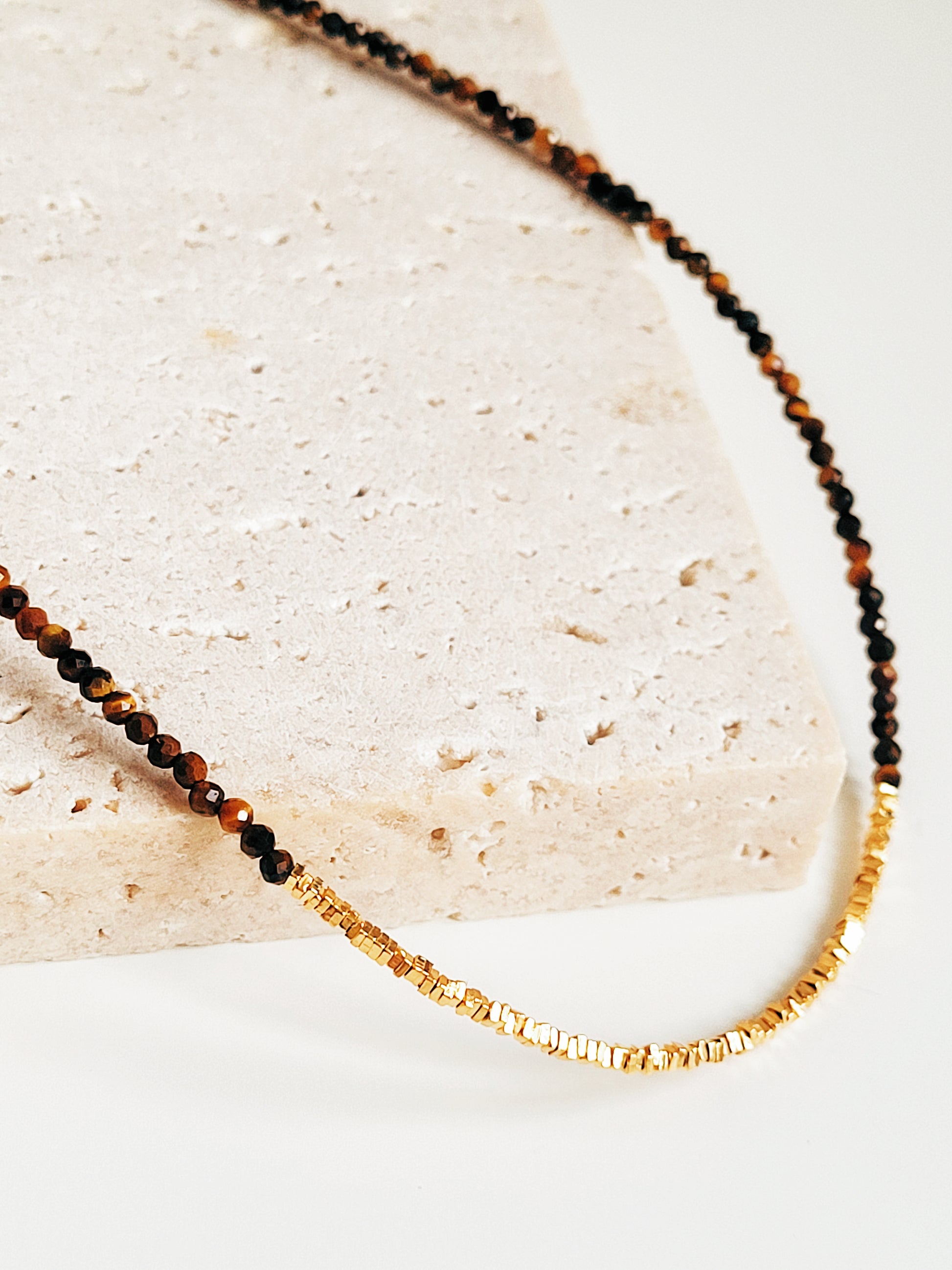 Close-up of a Tiger’s Eye beaded gemstone choker necklace with 22K gold vermeil nugget beads displayed on a natural stone surface