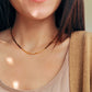Close-up of woman wearing Tiger’s Eye gemstone choker necklace with 22K gold vermeil nugget beads in natural sunlight