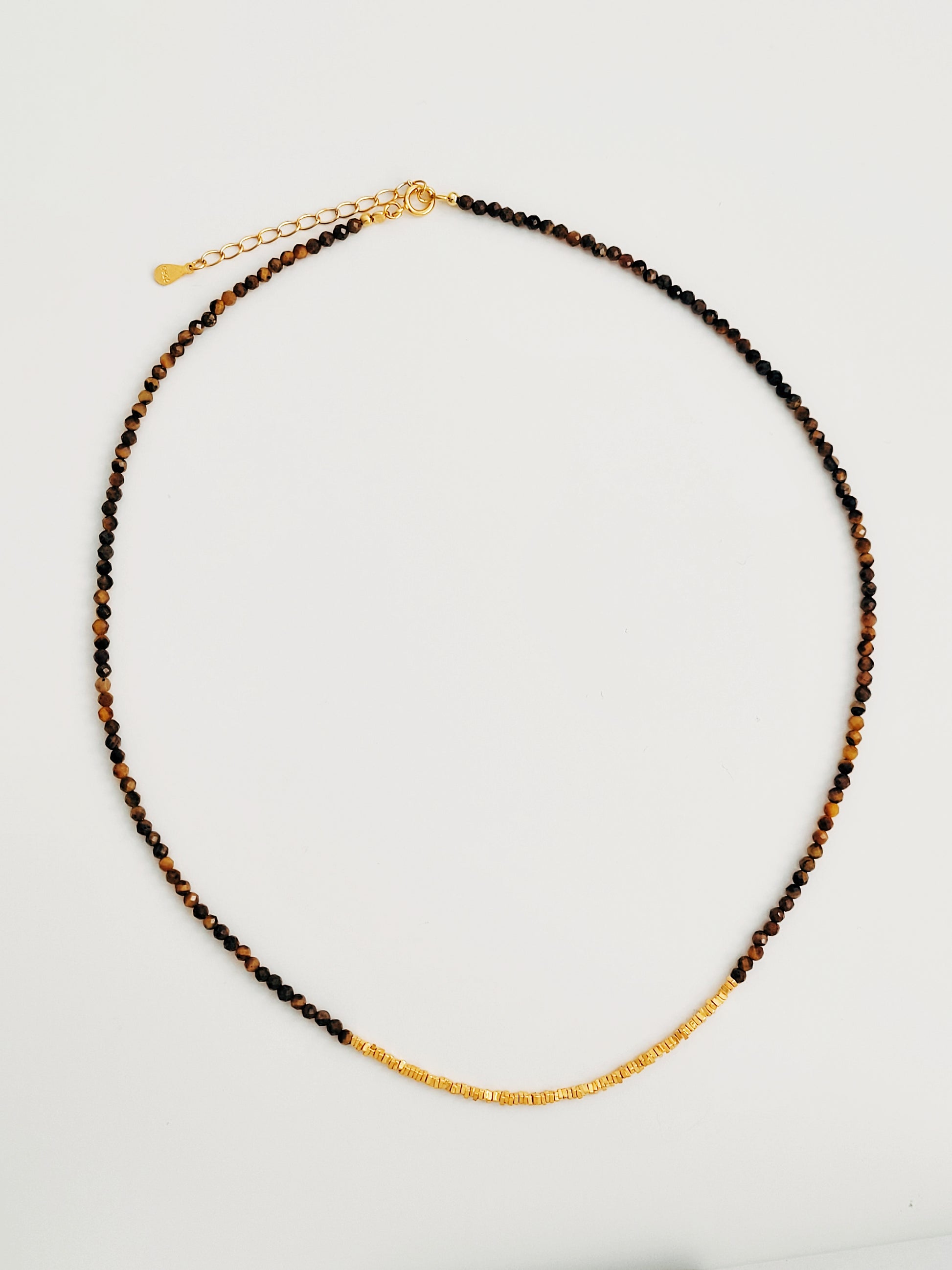 Close-up of a Tiger’s Eye gemstone choker necklace with 22K gold vermeil nugget beads on white surface