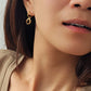 A model wearing a tiger's eye gemstone dangle earring in  minimalist and elegant style.